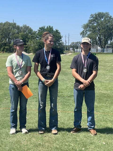 Three young shooters standing together wearing medals